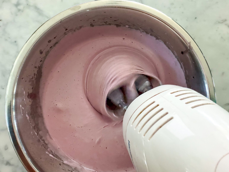 red wine marshmallow fluff in a bowl with a mixer