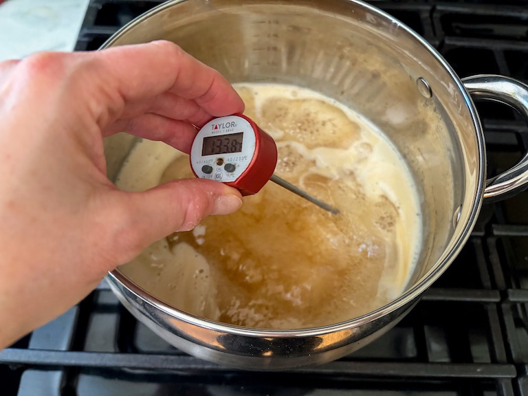 taking the temperature of a pan of hot sugar
