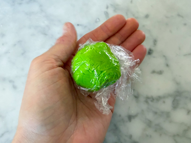 hand holding a ball of green fondant