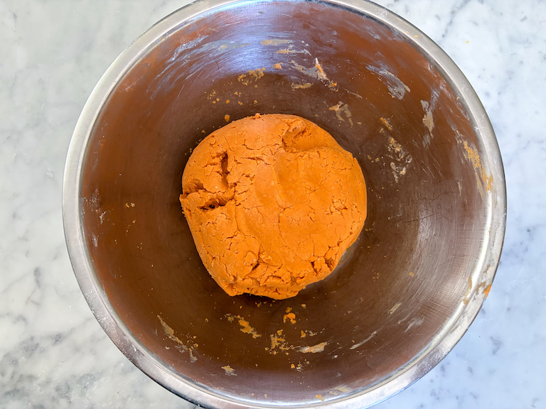 orange dough in a metal bowl