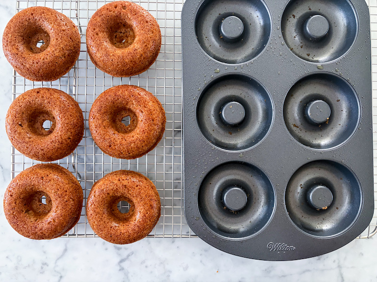 a donut pan and cider donuts on a wire rack
