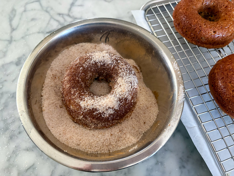 tossing donuts in cinnamon sugar