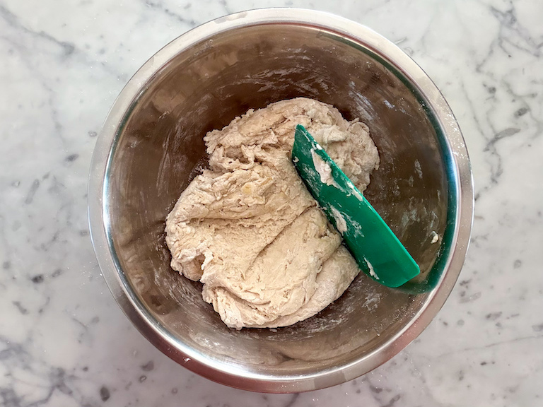 bread dough in a bowl with a bench scraper