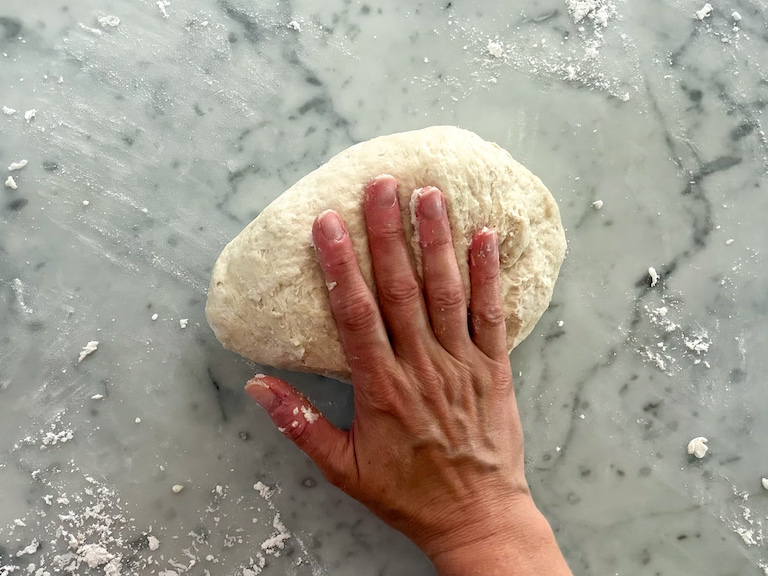 hand kneading a ball of bread dough