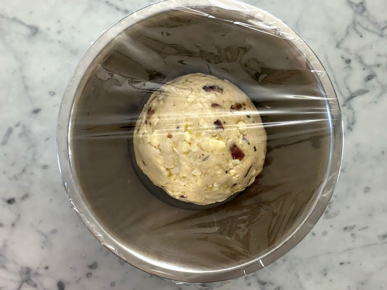 blue cheese bread dough in a bowl covered with plastic wrap