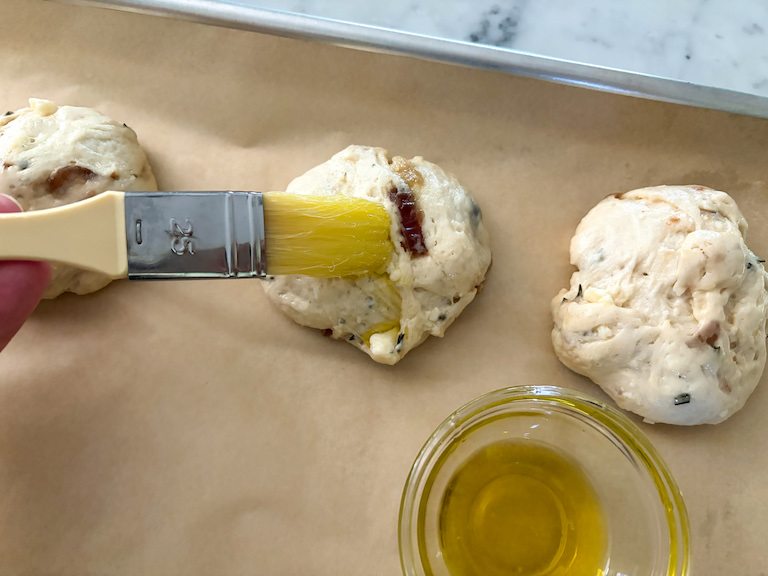 brushing olive oil over dinner rolls