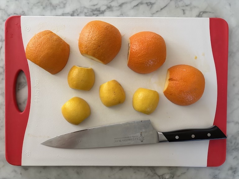 orange and lemon peels on a cutting board with a knife