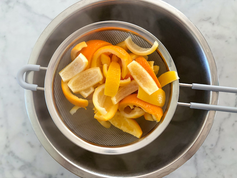 passing citrus peels through a mesh strainer
